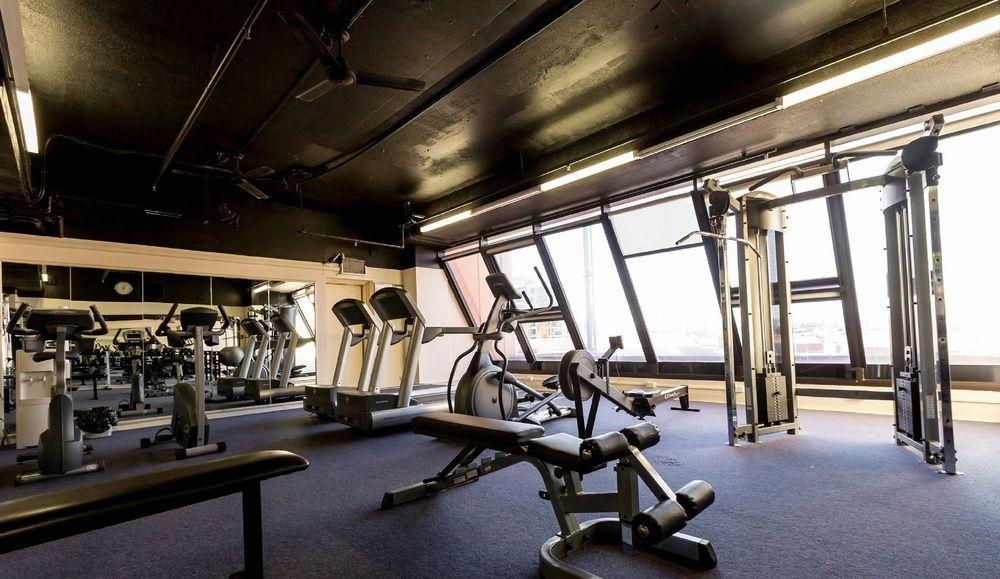 Stamford Grand Adelaide Hotel Glenelg Kültér fotó The photo shows a modern gym interior with large windows that provide natural light. The space features various exercise equipment, including treadmills, a weight machine, and a multi-purpose bench. The flooring is carpeted, and the overall decor is 