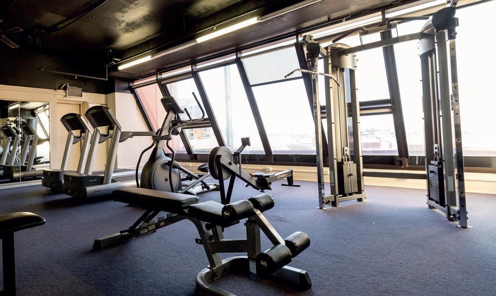 Stamford Grand Adelaide Hotel Glenelg Kültér fotó The photo shows a modern gym interior with several exercise machines. There are cardio machines, likely including treadmills and possibly an elliptical machine, along one side. In the center, there is a weight bench and a rowing machine. Additionally